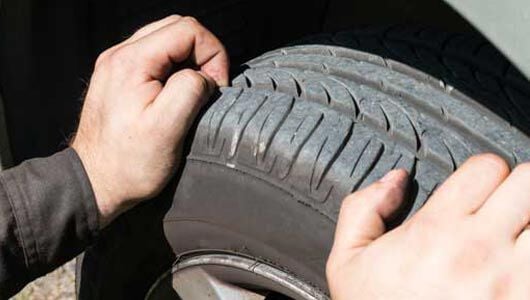 Hands on tire checking tread depth