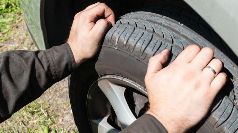 Hands on tire checking tread depth