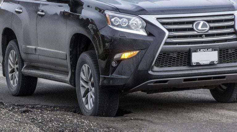 How can potholes damage your vehicle and tires? Vehicle going into a pothole on road