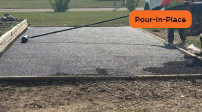 A man rolling out recycled rubber product with grass in the background.