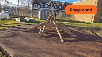 A wooden climbing structure on top of a brown coloured recycled rubber surface.