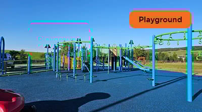 A large blue and green playground with bright blue recycled rubber play surface.