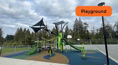 A fully rubberized playground surfacing in green, blue, and brown underneath new play equipment at an elementary school.